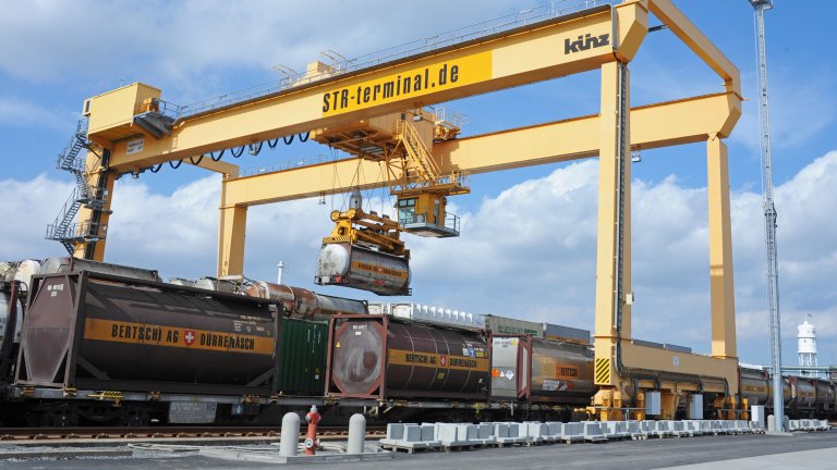 Logistik für Kunststoffe und Chemie Ein Brückenkran entlädt einen Zug mit Chemiebehältern