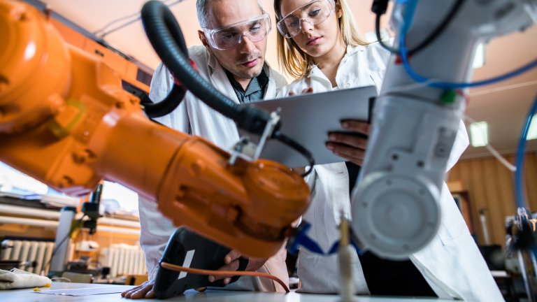 Forscher im Labor vor Roboterarmen